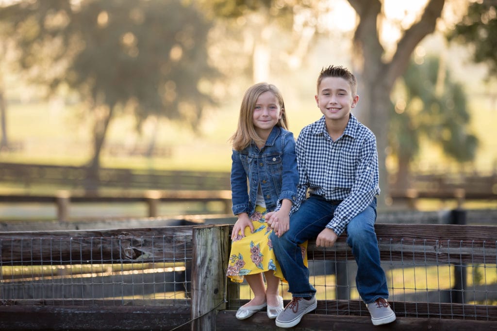 siblings on fence at horse farm photo session