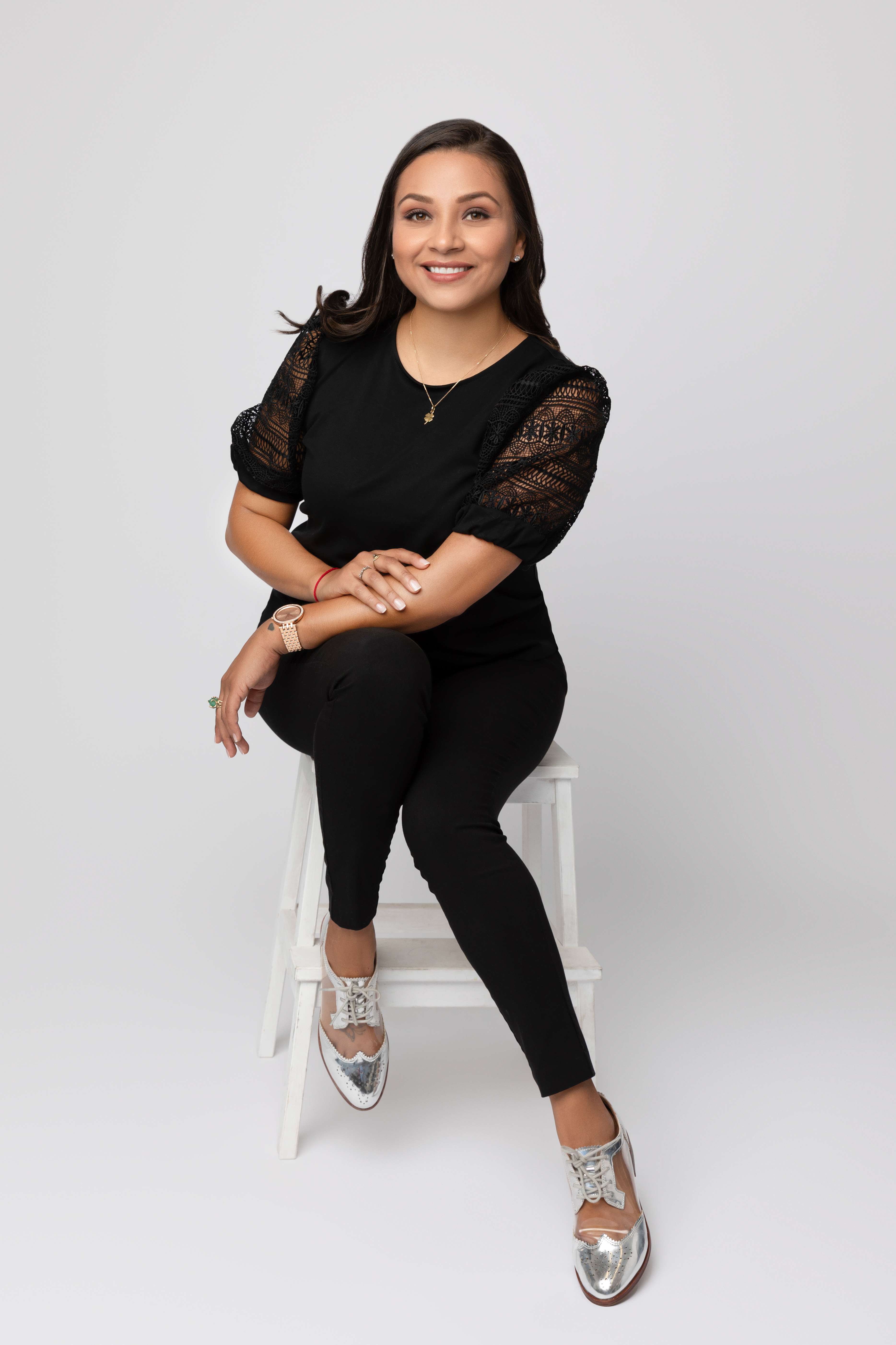 Dark haired woman sitting on low stool wearing black clothing