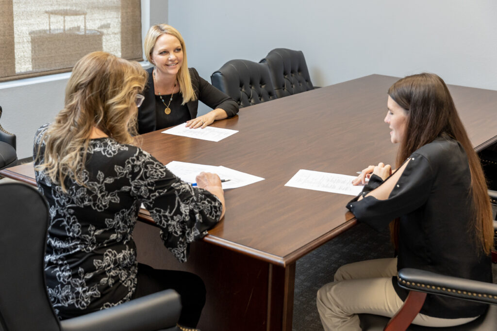 3 women sitting at a board room table.